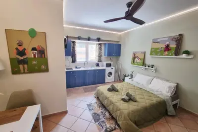 a bedroom with a bed and a kitchen with blue cabinets at Pavlina Artistic Βeauty 33sqm metro 7' in Athens