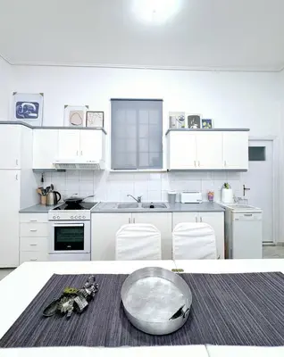 a white kitchen with white cabinets and a table at 26 HoMe in Athens
