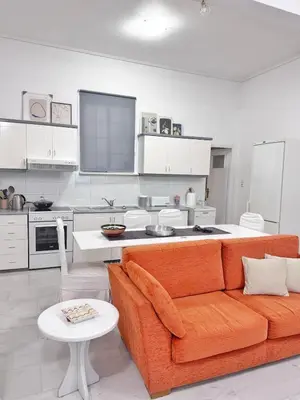 a living room with an orange couch and a kitchen at 26 HoMe in Athens