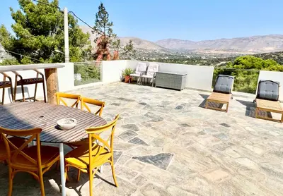 a patio with a wooden table and chairs at 2 bedroom self-contained apartment and swimming pool at Palm Tree Villa in Anavissos