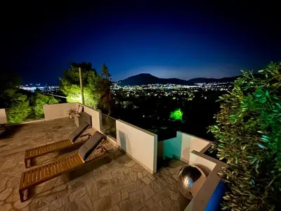 a bench sitting on top of a balcony at night at 2 bedroom self-contained apartment and swimming pool at Palm Tree Villa in Anavissos
