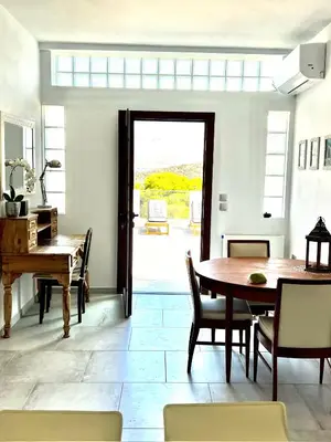 a dining room with a table and a piano at 2 bedroom self-contained apartment and swimming pool at Palm Tree Villa in Anavissos