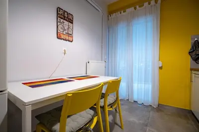 a kitchen with a white table and yellow chairs at Backyard Bliss in Ano Patisia by ΜΡS in Athens