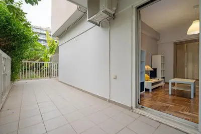 a balcony with a white wall and a table at Backyard Bliss in Ano Patisia by ΜΡS in Athens