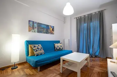 a living room with a blue couch and a table at Backyard Bliss in Ano Patisia by ΜΡS in Athens