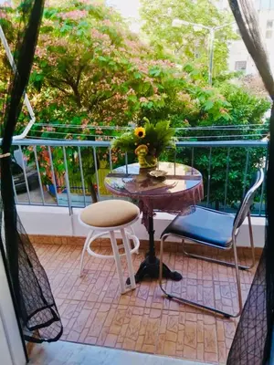 a balcony with a table and two chairs and a vase of flowers at Filio House-Feels Like Home in Athens