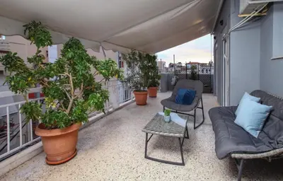 a balcony with a couch and chairs and potted plants at Jocasta - Cocoon Apartment Near Metro Station in Athens