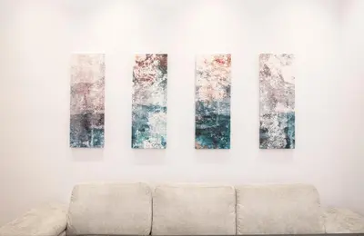 a couch in a room with four paintings on a wall at The New Flat 183 - Ground floor, fully renovated in Athens