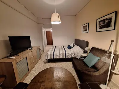 a bedroom with a bed and a couch and a television at Central Modern Stay Apartment-5min walk from metro in Athens