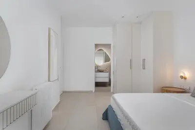 a white bedroom with a bed and a bathroom at Arche Residence Glyfada in Athens