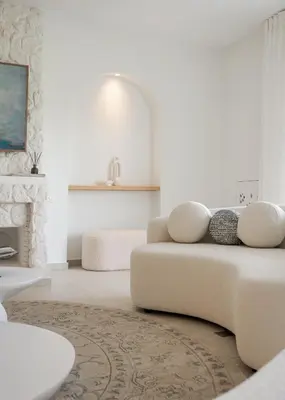 a white living room with a couch and a fireplace at Arche Residence Glyfada in Athens