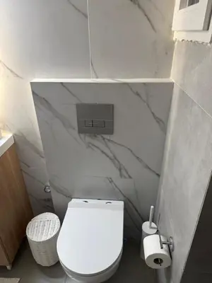 a bathroom with a white toilet and marble walls at The Athenian Chic in Athens
