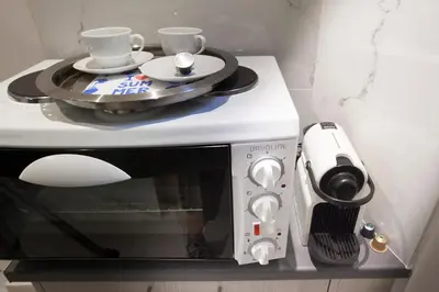 a microwave with two cups on top of it at Cozy Apartment Next To PIRAEUS PORT in Piraeus