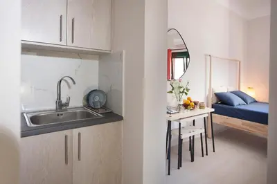 a kitchen with a sink and a table with a bed at Cozy Apartment Next To PIRAEUS PORT in Piraeus