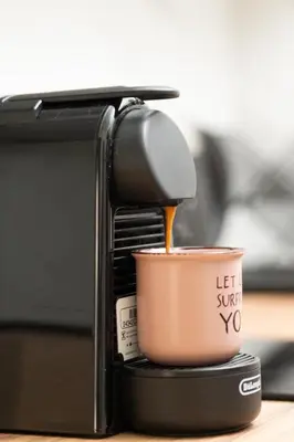 a cup of coffee is being poured into a toaster at Modern Rooms Pagrati in Athens