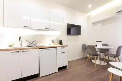 a kitchen with white cabinets and a table and chairs at Modern Rooms Pagrati in Athens