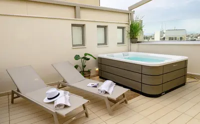 a hot tub on a balcony with two chairs at Sky Suite with View & Jacuzzi in Athens