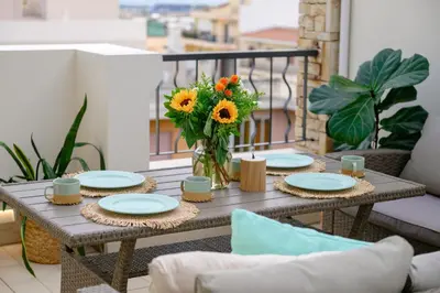 a table with sunflowers in a vase on a balcony at Sky Suite with View & Jacuzzi in Athens