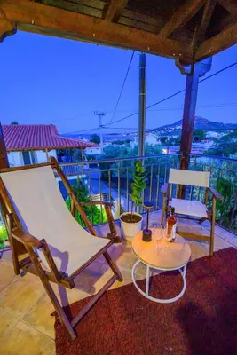 a rocking chair and a table on a balcony at NoamansHouse SeaView near Airport in Artemida