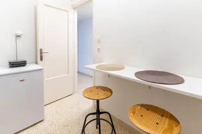 a white kitchen with a stool and a counter at The Homely Hideaway in Athens