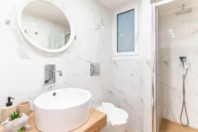 a white bathroom with a sink and a mirror at The Homely Hideaway in Athens