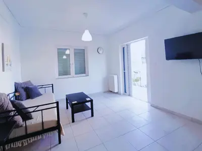 a white living room with a couch and a tv at City Center 2-Bedroom Sun home in Athens