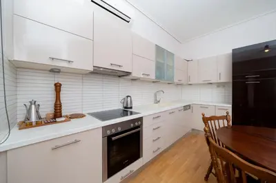 a kitchen with white cabinets and a wooden table at Casa Tierra Near ATH Airport in Markopoulo