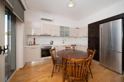 a kitchen with a table and chairs and a refrigerator at Casa Tierra Near ATH Airport in Markopoulo