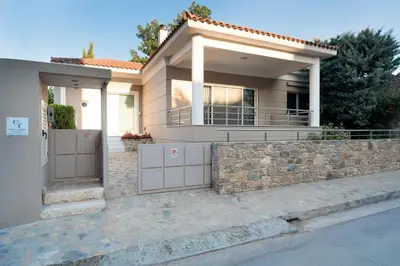 a house with a stone wall and a fence at Casa Tierra Near ATH Airport in Markopoulo