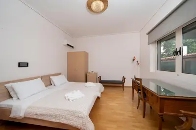 a bedroom with a bed and a desk and a window at Casa Tierra Near ATH Airport in Markopoulo