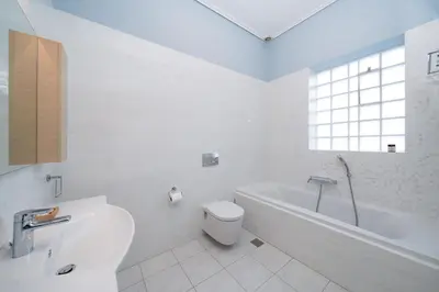 a white bathroom with a tub and a toilet and a sink at Casa Tierra Near ATH Airport in Markopoulo