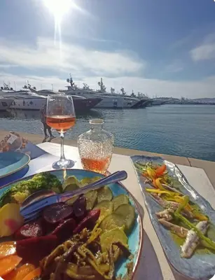 a table with a plate of food and a glass of wine at Spacious 2BR by Floisvos Beach Saltwater Balcony in Athens