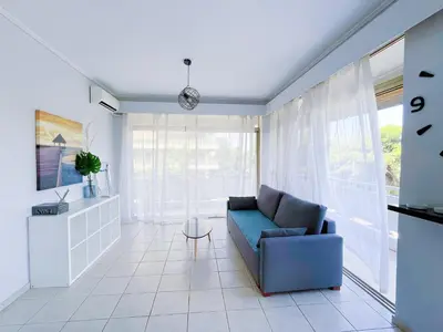a living room with a blue couch and a window at Spacious 2BR by Floisvos Beach Saltwater Balcony in Athens