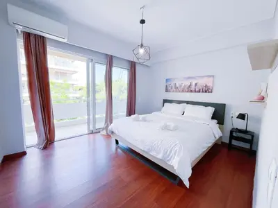 a bedroom with a large white bed and a large window at Spacious 2BR by Floisvos Beach Saltwater Balcony in Athens