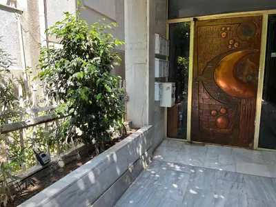 a door to a building with a tree next to it at Spacious 2BR by Floisvos Beach Saltwater Balcony in Athens