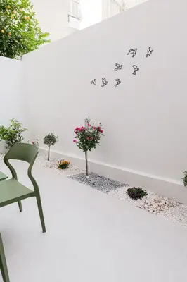 a green chair in front of a white wall with birds decals at ALMARLIVING Stylish 2BR Apartment in Ilioupolis in Athens
