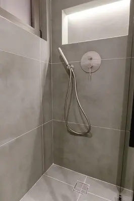 a shower with a hose attached to a wall at ALMARLIVING Stylish 2BR Apartment in Ilioupolis in Athens
