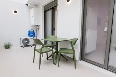 a green table and chairs in a room with a window at ALMARLIVING Stylish 2BR Apartment in Ilioupolis in Athens