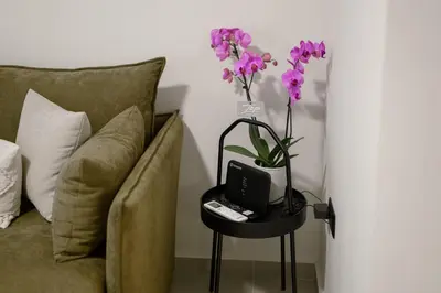 a vase of flowers on a table next to a couch at ALMARLIVING Stylish 2BR Apartment in Ilioupolis in Athens