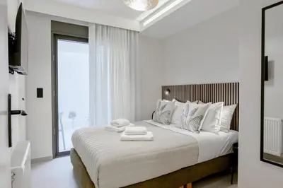 a white bedroom with a large bed with white pillows at ALMARLIVING Stylish 2BR Apartment in Ilioupolis in Athens