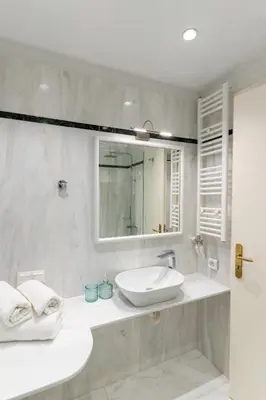 a white bathroom with a sink and a mirror at Athens Plaka Acropolis Suites in Athens