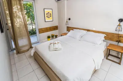 a bedroom with a large white bed with two bags on it at Aris Athens Suites in Athens