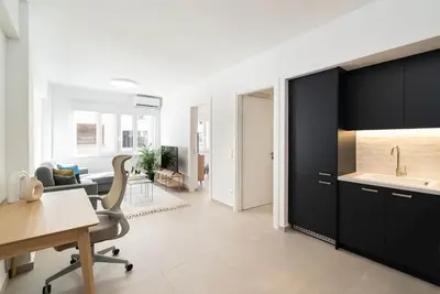 a kitchen with black cabinets and a sink and a desk at Athens Urban Apartment in Athens