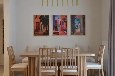 a dining room table and chairs with paintings on the wall at Prestige Lifestyle 3bd Apt in Kolonaki in Athens