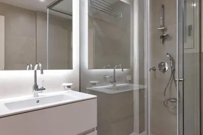 a white bathroom with a sink and a shower at Prestige Lifestyle 3bd Apt in Kolonaki in Athens