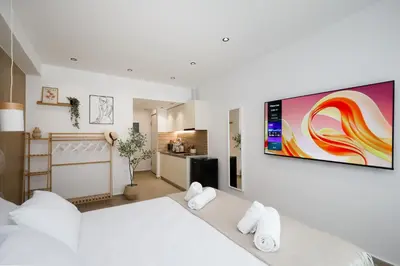 a bedroom with a white bed with a large television on the wall at O Suite - 105 in Athens