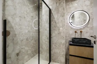 a bathroom with a shower with a sink and a mirror at O Suite - 105 in Athens