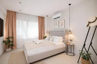 a white bedroom with a white bed and a window at O Suite - 106 in Athens
