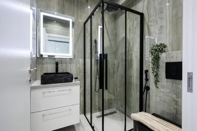 a bathroom with a shower with a sink and a mirror at O Suite - 106 in Athens