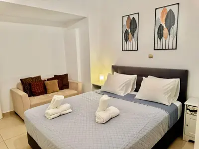 a bedroom with a bed with two white chairs on it at Marina Zeas Spacious Two Bedroom Apartment in Piraeus